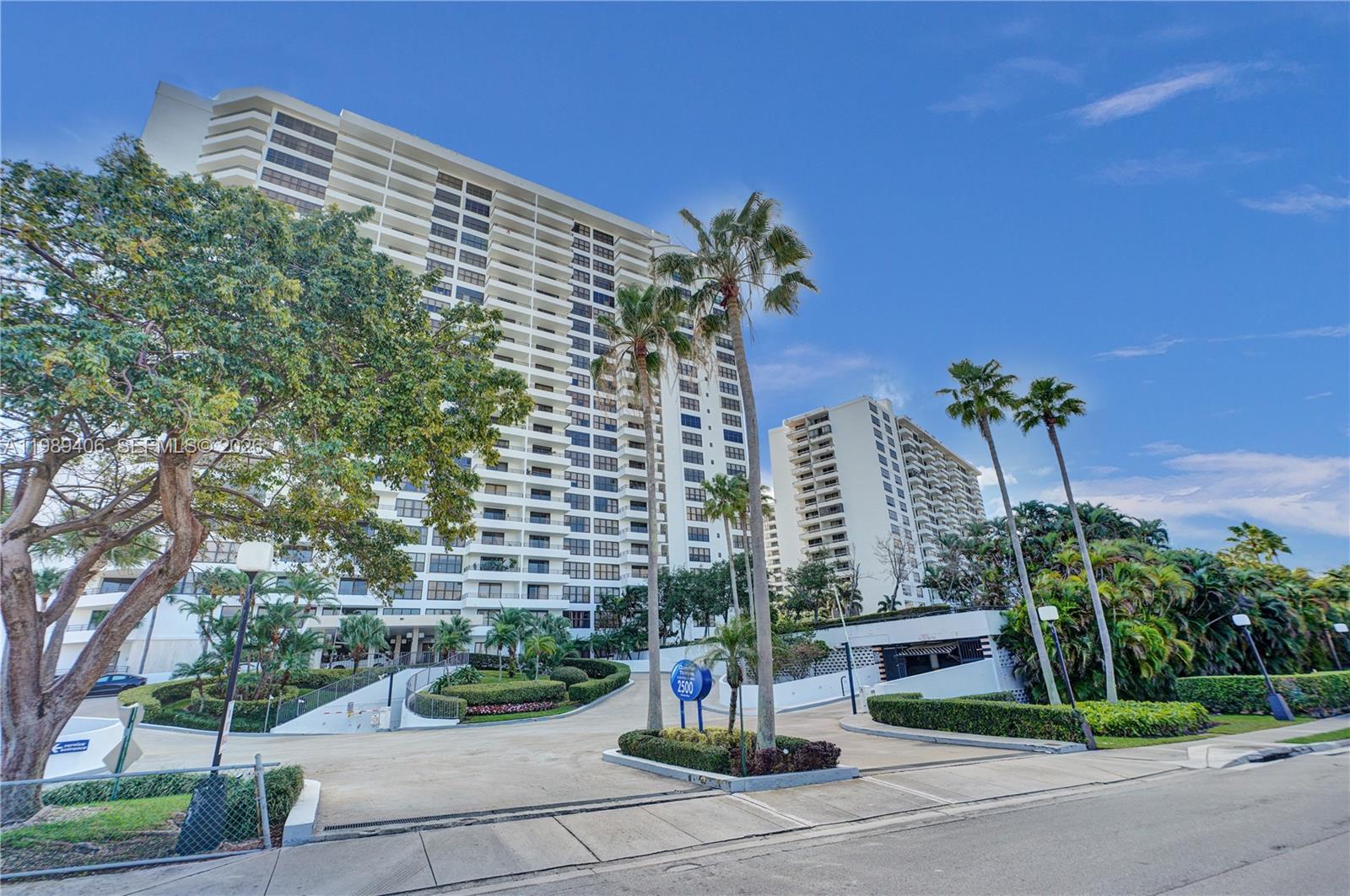 A tall residential high-rise building stands behind a paved driveway with palm trees — 2500 Parkview Dr # 808, Hallandale Beach FL 33009, HALLANDALE BEACH, FL