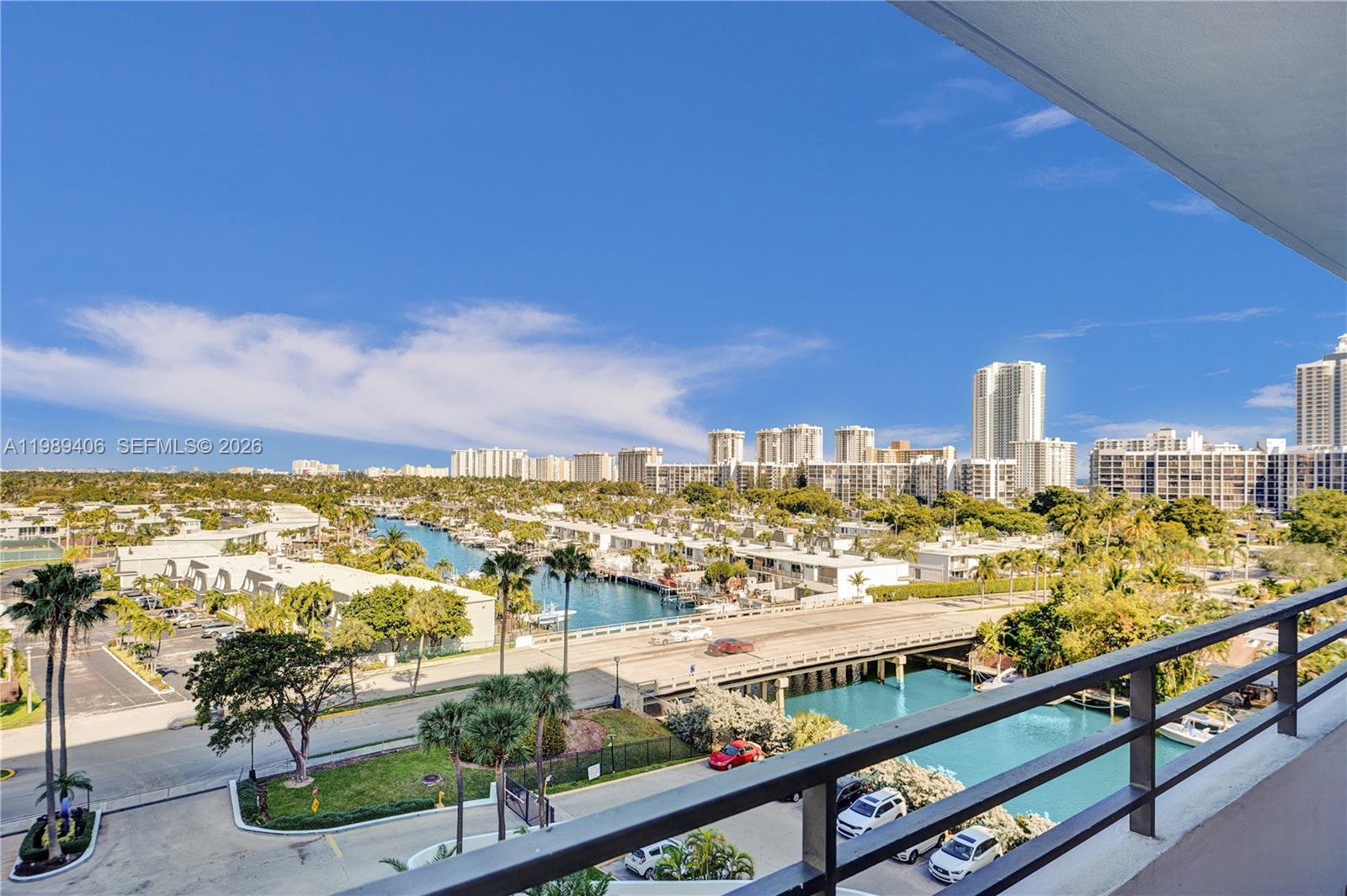 A high-angle view from a balcony overlooks a canal, a bridge, and city buildings — 2500 Parkview Dr # 808, Hallandale Beach FL 33009, HALLANDALE BEACH, FL