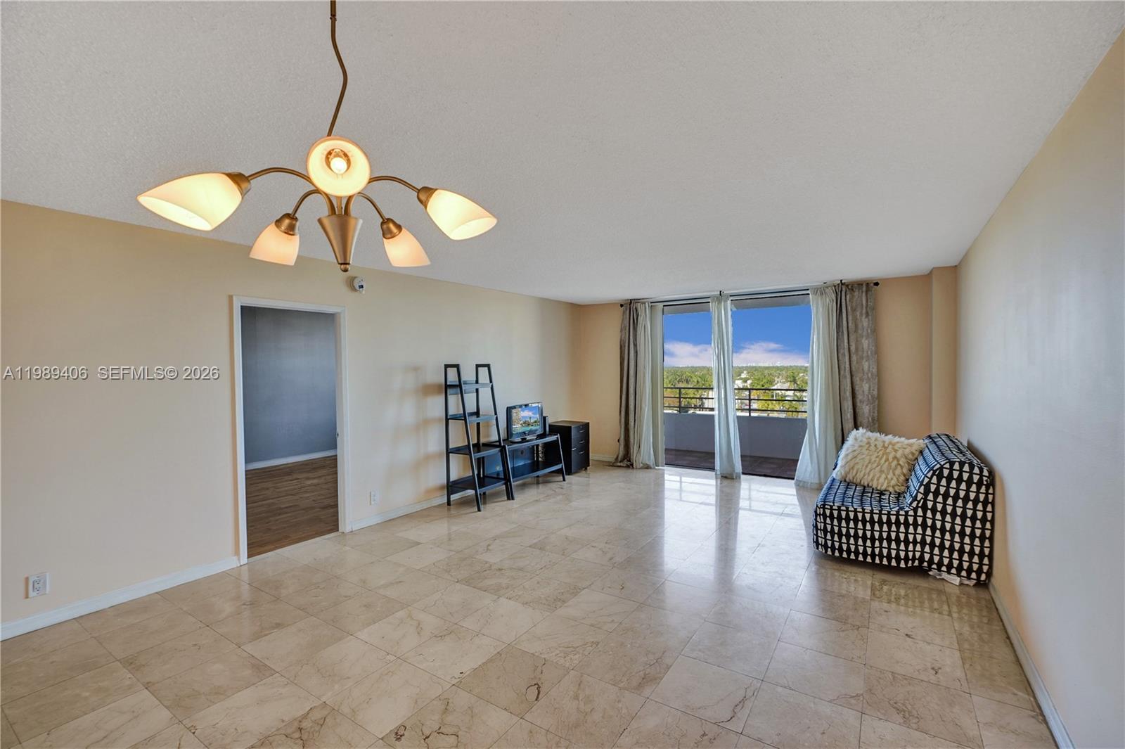 A living room features marble tile flooring, a modern chandelier, and a balcony with views — 2500 Parkview Dr # 808, Hallandale Beach FL 33009, HALLANDALE BEACH, FL