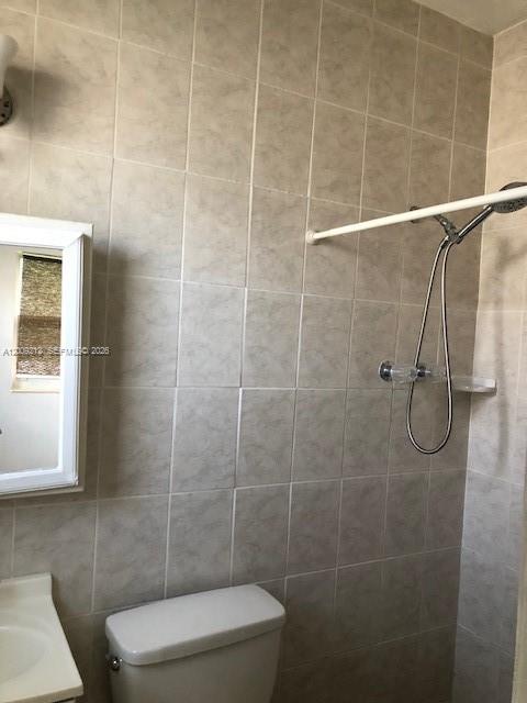 A bathroom features a white toilet, a wall-mounted mirror, and a shower with tiled walls — 471 SW 10th St # 5, Miami FL 33130, MIAMI, FL