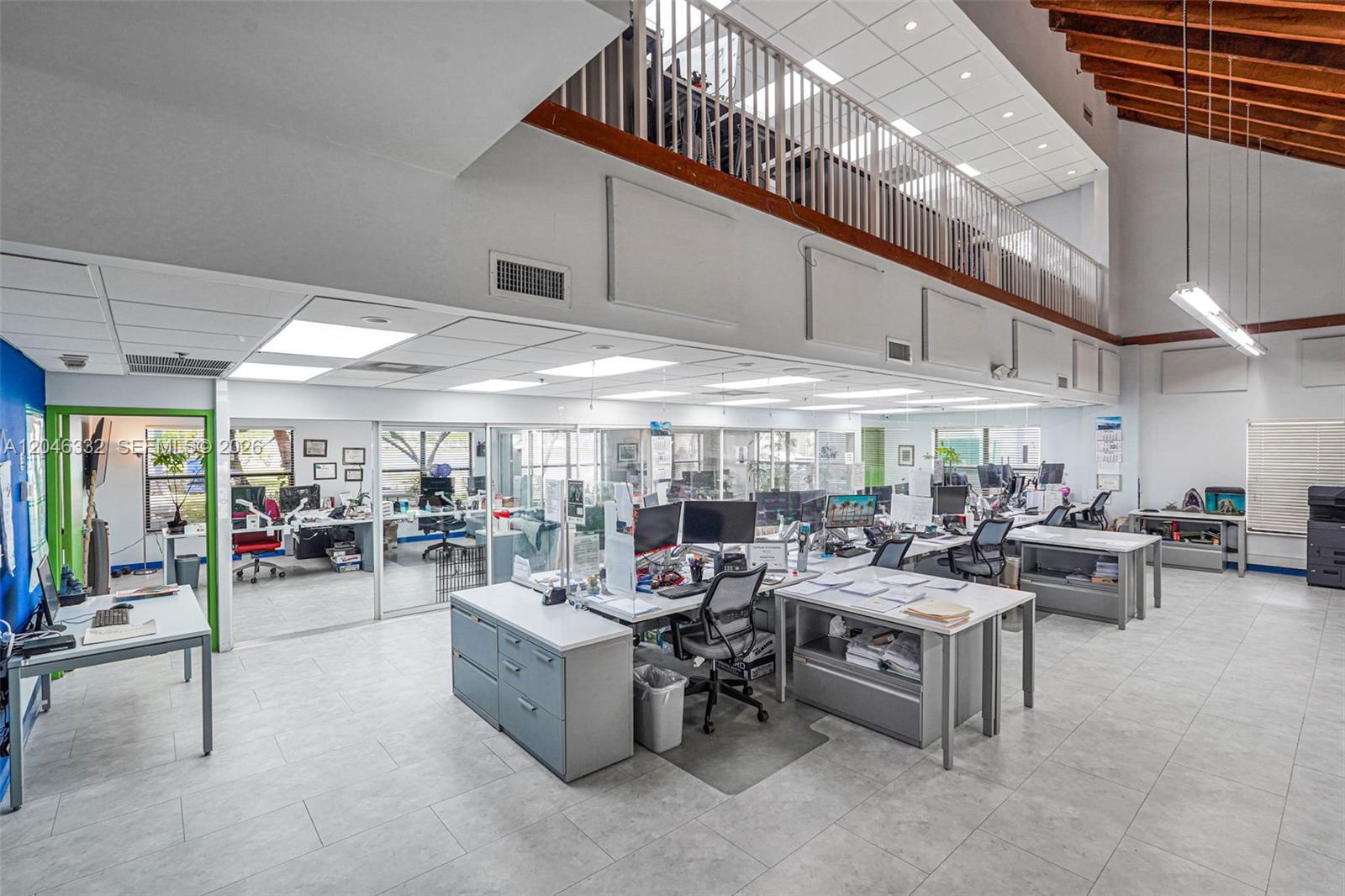 An open-plan office features multiple workstations, glass partitions, tiled floors, and a mezzanine level — 1400 NW 79th Ave, Doral FL 33126, DORAL, FL