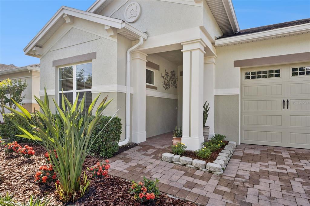 A beige house exterior features a paved walkway, a covered entryway, and a garage — 4902 W FOUNTAINWOOD DRIVE, ST CLOUD, FL