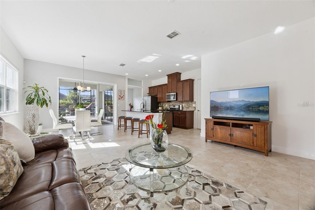 An open-concept living room and kitchen featuring tile flooring, dark wood cabinetry, and a television — 4902 W FOUNTAINWOOD DRIVE, ST CLOUD, FL