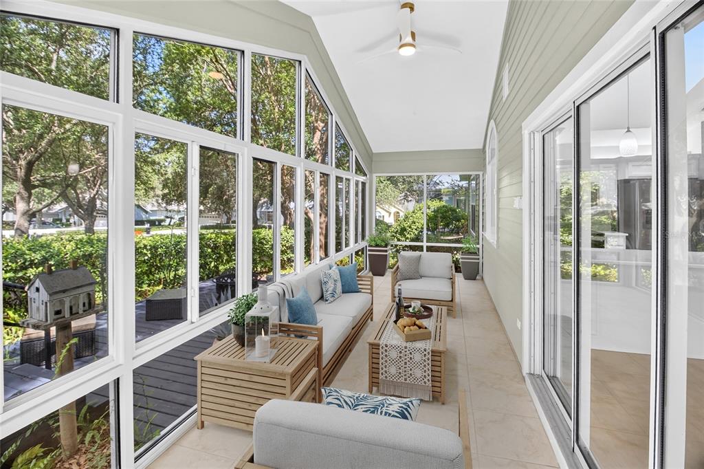 A sunroom with large windows, light tile flooring, and outdoor furniture overlooking a wooded area — 10549 NW 32ND ROAD, GAINESVILLE, FL
