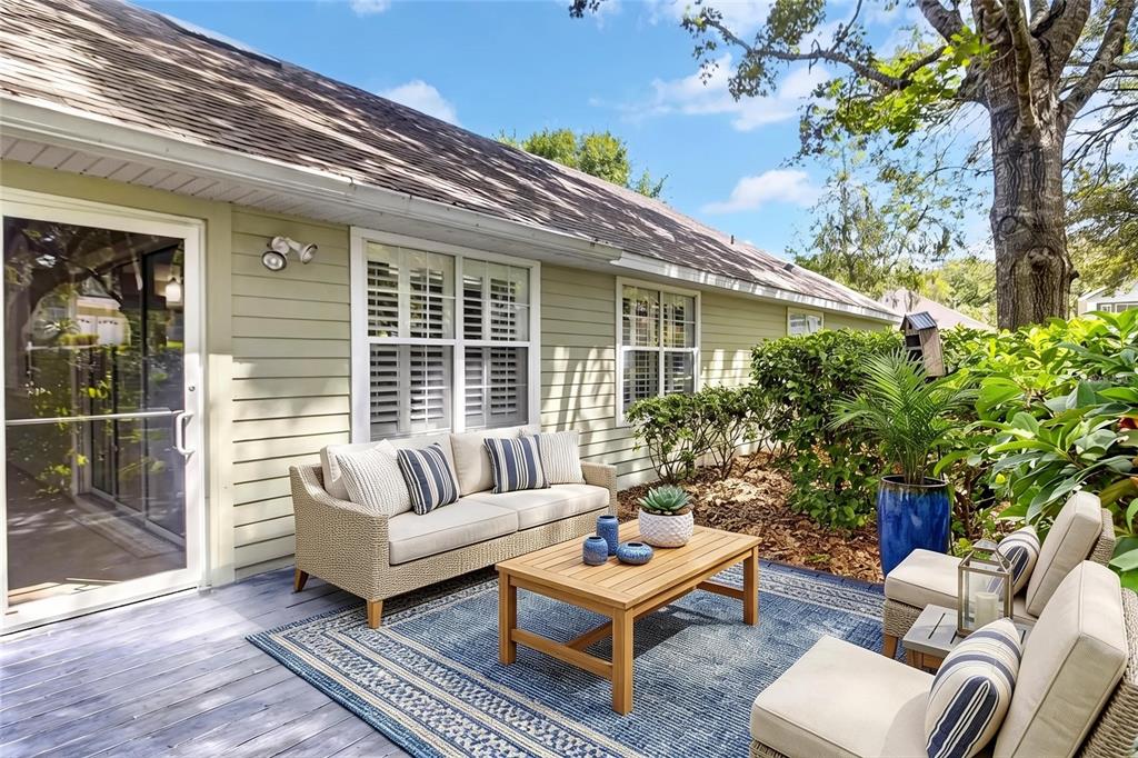 A patio with a wicker sofa, two chairs, a wooden coffee table, and a blue rug — 10549 NW 32ND ROAD, GAINESVILLE, FL