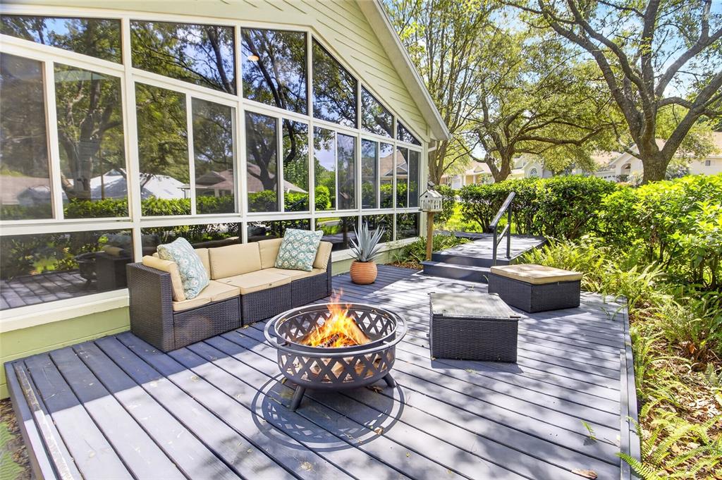 A gray wooden deck features a fire pit, wicker patio furniture, and large glass windows — 10549 NW 32ND ROAD, GAINESVILLE, FL