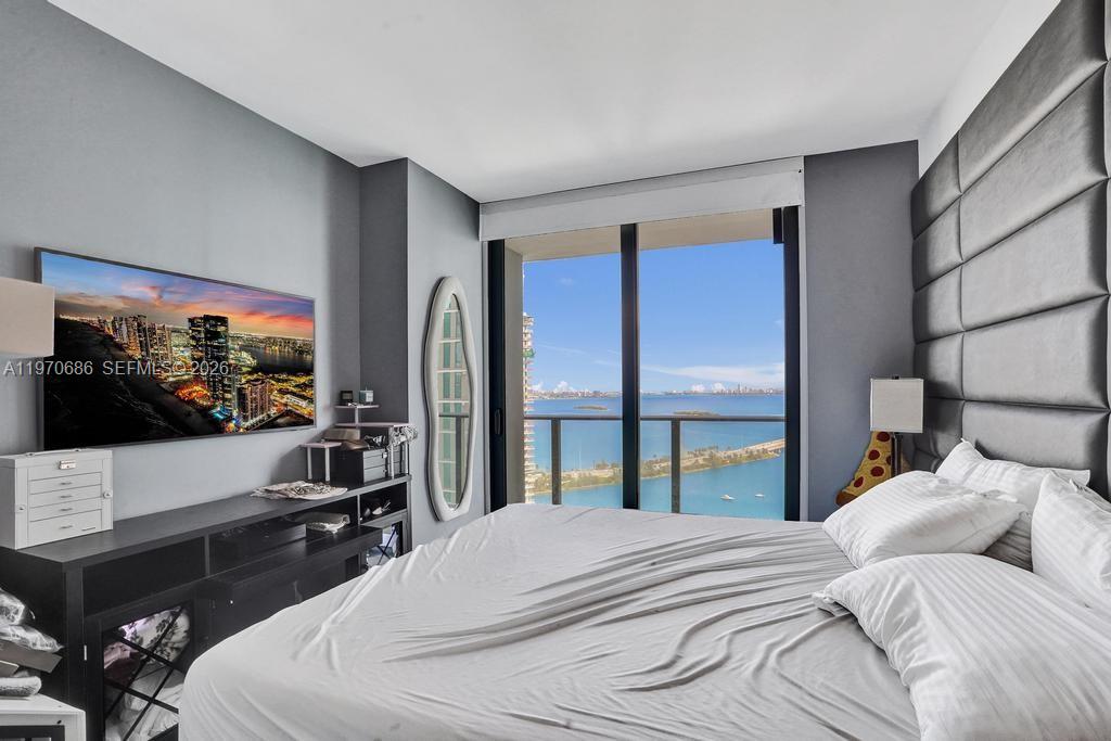 A bedroom features a large bed, a wall-mounted television, and floor-to-ceiling windows overlooking water — 501 NE 31st St # 3306, Miami FL 33137, MIAMI, FL