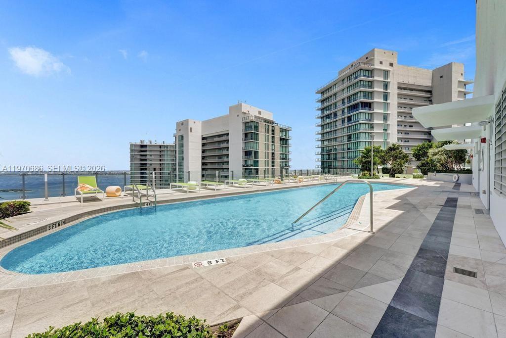 An outdoor swimming pool with lounge chairs overlooks a bay and tall residential buildings — 501 NE 31st St # 3306, Miami FL 33137, MIAMI, FL