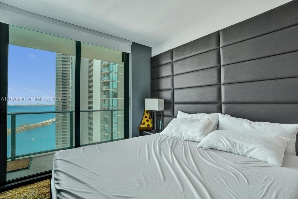 A bedroom features a large upholstered headboard, white bedding, and a balcony overlooking the ocean — 501 NE 31st St # 3306, Miami FL 33137, MIAMI, FL