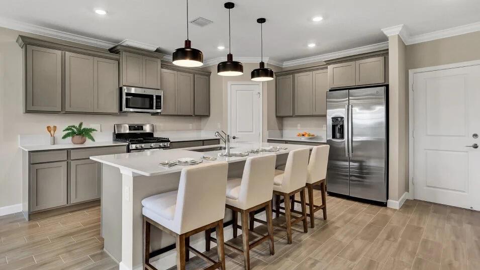 A modern kitchen features gray cabinets, stainless steel appliances, a white island, and bar stools — 19868 Whispering Creek Road, FL 33470, FL