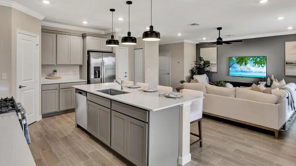 A modern open-concept kitchen with a large island and gray cabinets overlooks a living room — 19868 Whispering Creek Road, FL 33470, FL