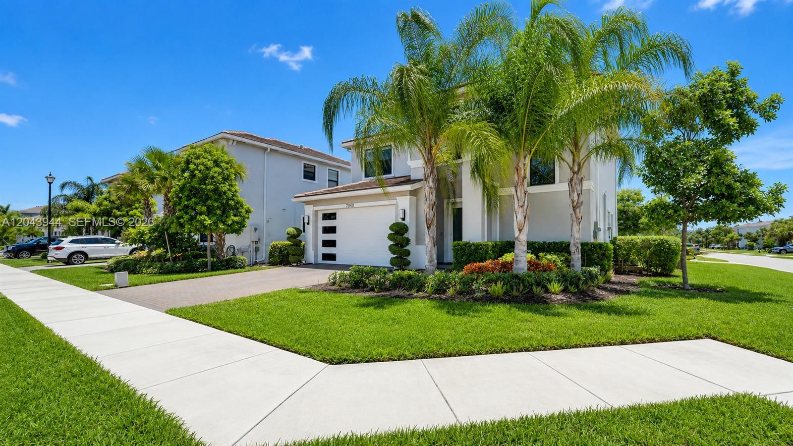 A two-story suburban house features a white garage, palm trees, and a paved driveway — 7349 Stella Ln, Lake Worth FL 33463, LAKE WORTH, FL