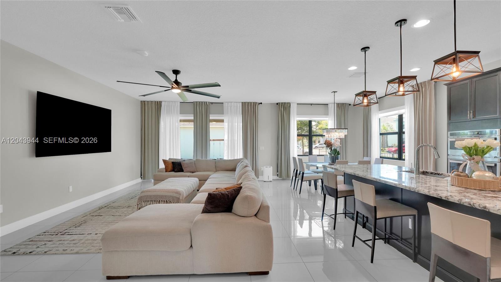 An open-concept living room and kitchen feature a large sectional sofa and kitchen island — 7349 Stella Ln, Lake Worth FL 33463, LAKE WORTH, FL
