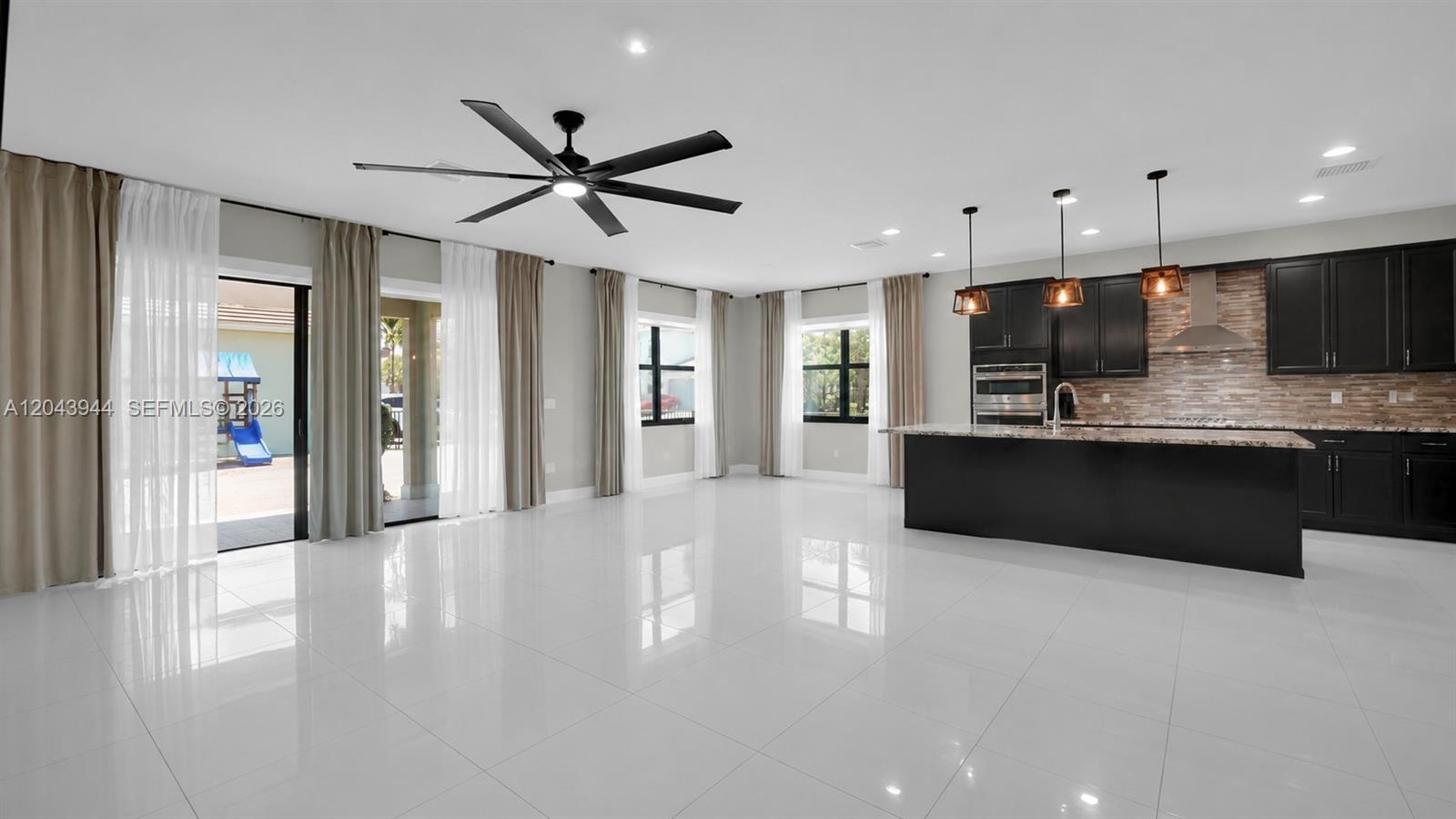 A spacious open-concept kitchen and living area features white tile floors and dark cabinetry — 7349 Stella Ln, Lake Worth FL 33463, LAKE WORTH, FL