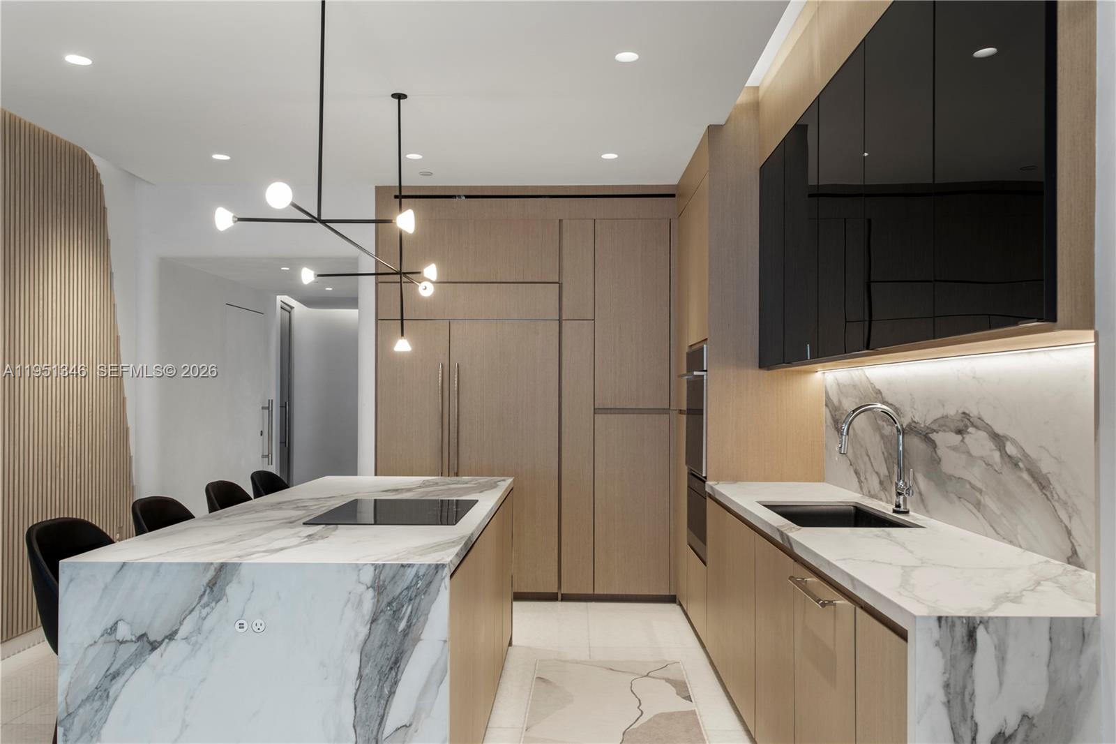A modern kitchen features a marble island, wood cabinetry, black upper cabinets, and recessed lighting — 851 NE 1st Ave # 3411, Miami FL 33132, MIAMI, FL