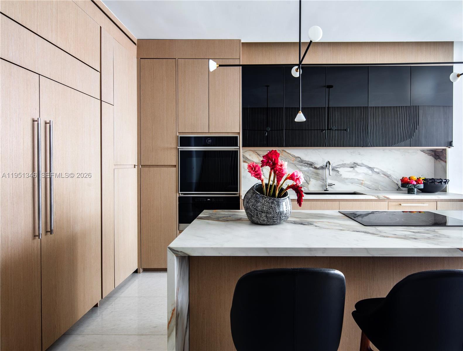 A modern kitchen features light wood cabinetry, black upper cabinets, and a marble-topped island — 851 NE 1st Ave # 3411, Miami FL 33132, MIAMI, FL