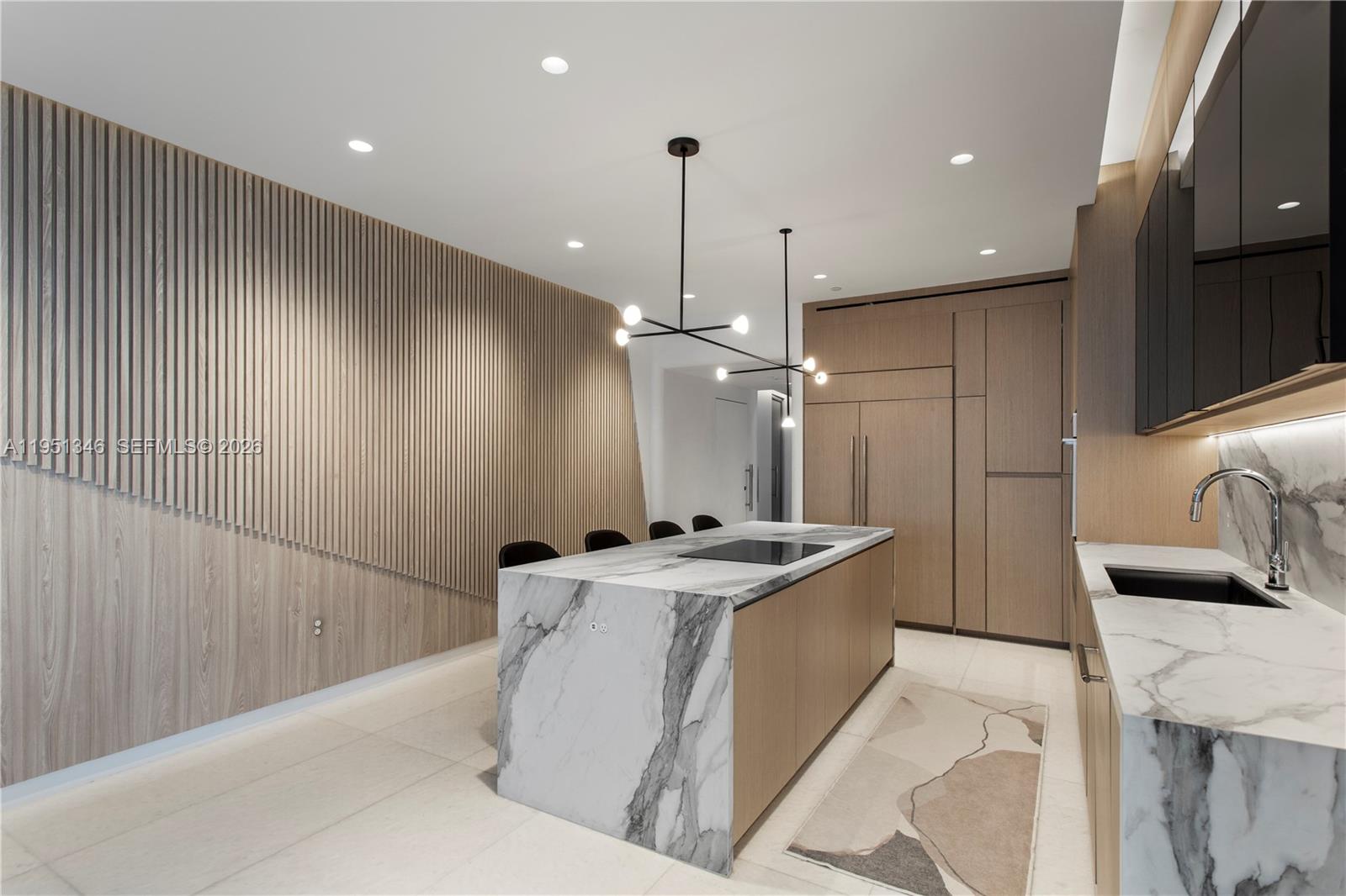 A modern kitchen features a marble island, wood-slatted wall paneling, and integrated cabinetry — 851 NE 1st Ave # 3411, Miami FL 33132, MIAMI, FL