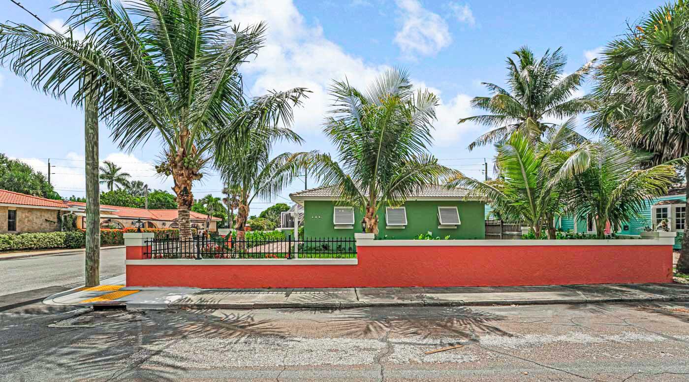 A green house sits behind a bright orange wall with a black metal fence — 532 N Palmway, FL 33460, FL