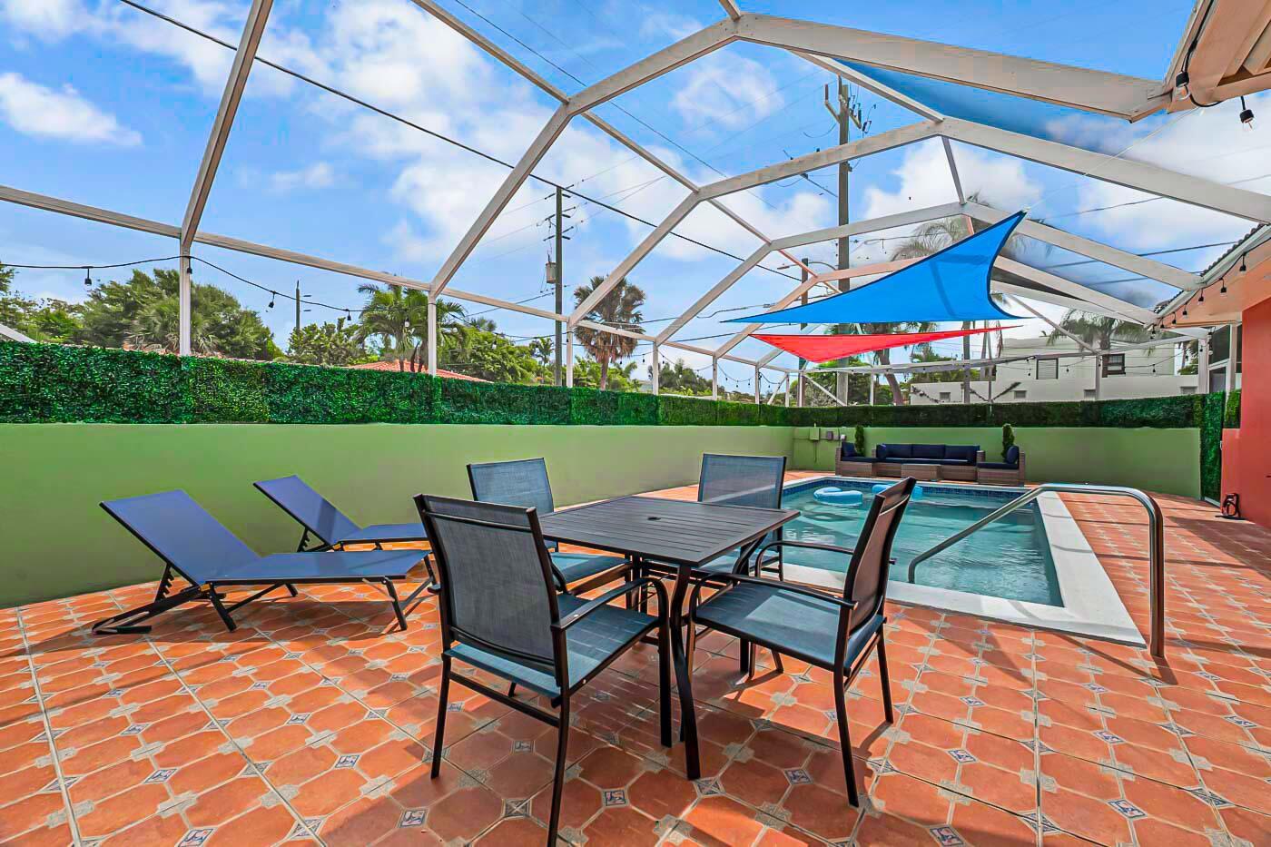 A screened-in patio features a swimming pool, dining set, lounge chairs, and tiled flooring — 532 N Palmway, FL 33460, FL