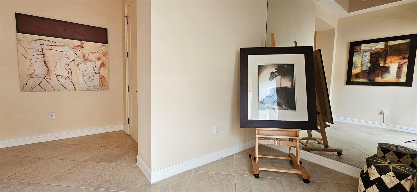 A room with tiled floors, beige walls, artwork, and an easel holding a framed picture — 16117 Emerald Estates Drive, Weston FL 33331, WESTON, FL