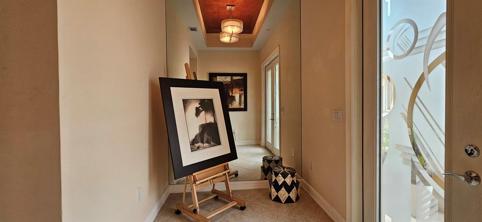 A hallway features a large mirror, a framed picture on an easel, and tiled floors — 16117 Emerald Estates Drive, Weston FL 33331, WESTON, FL