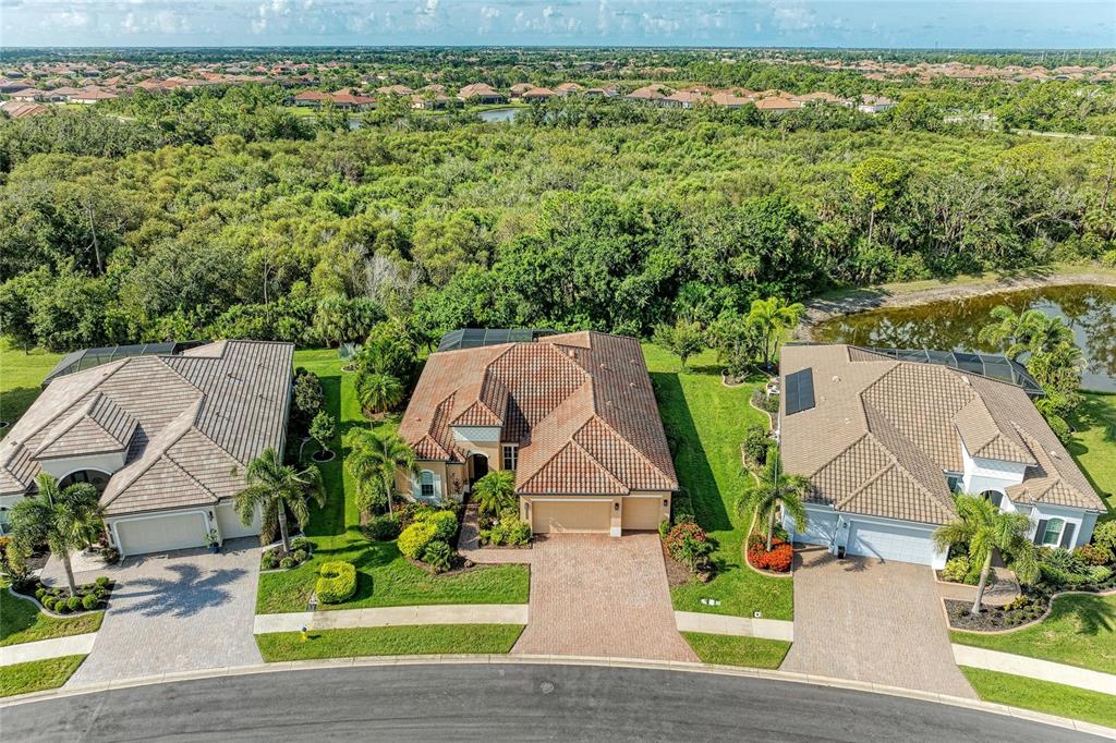 An aerial view shows three suburban houses with tiled roofs and driveways facing a street — 13440 CAMPANILE COURT, VENICE, FL