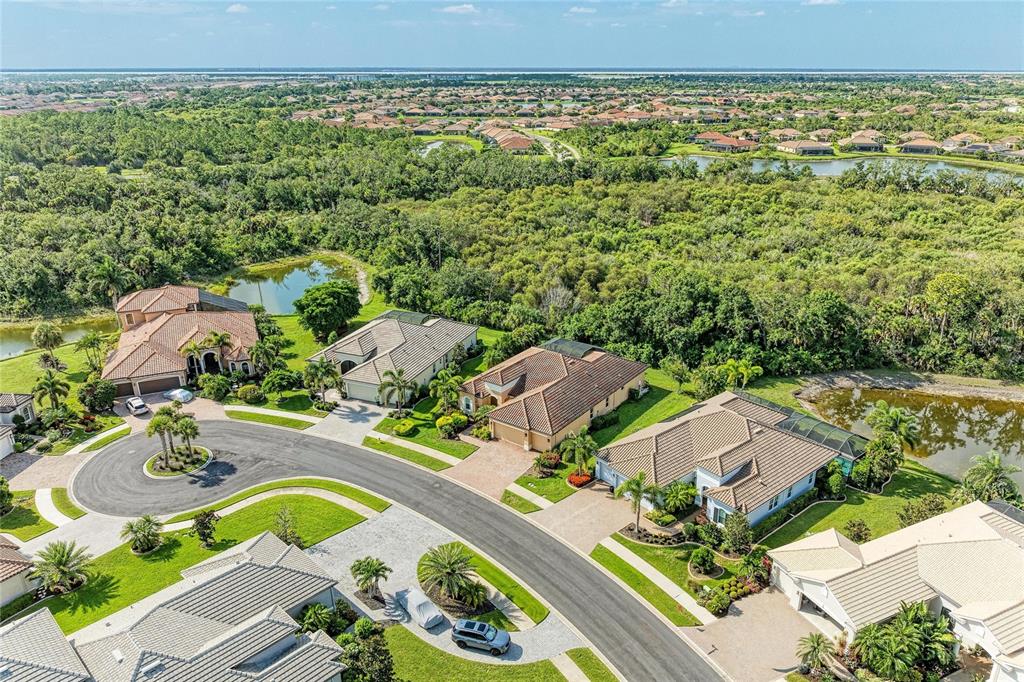 An aerial view shows several suburban houses with tiled roofs situated near ponds and woods — 13440 CAMPANILE COURT, VENICE, FL