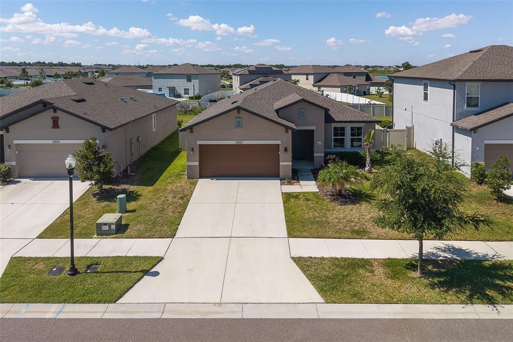 An aerial view shows a single-story suburban house with a brown garage and concrete driveway — 13512 PALMERA VISTA DRIVE, RIVERVIEW, FL