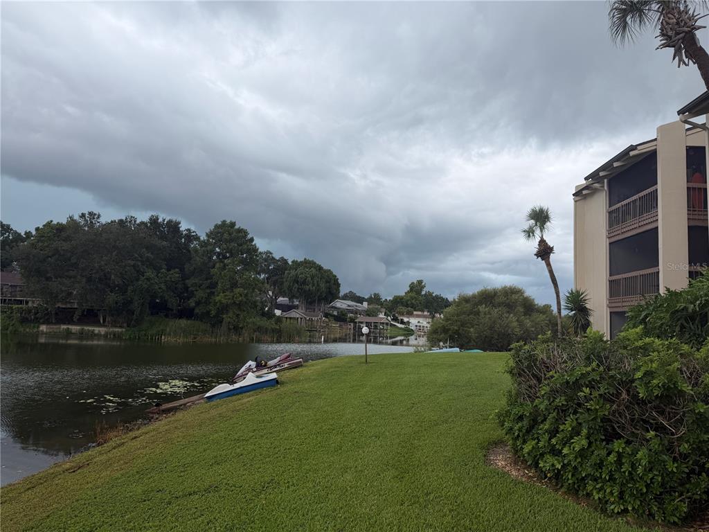 A wooden dock extends into a lake between two large trees with a grassy foreground — 620 ORANGE DRIVE UNIT 227, ALTAMONTE SPRINGS, FL