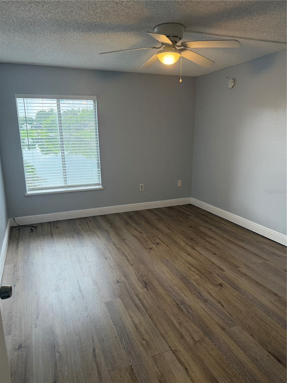 An open-concept living area features wood-look flooring, a kitchen pass-through, and a white entry door — 620 ORANGE DRIVE UNIT 227, ALTAMONTE SPRINGS, FL
