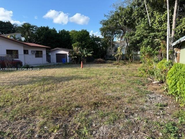 An empty, grassy lot sits adjacent to a residential house and a detached garage — 1121 NW 2nd St, Miami FL 33128, MIAMI, FL