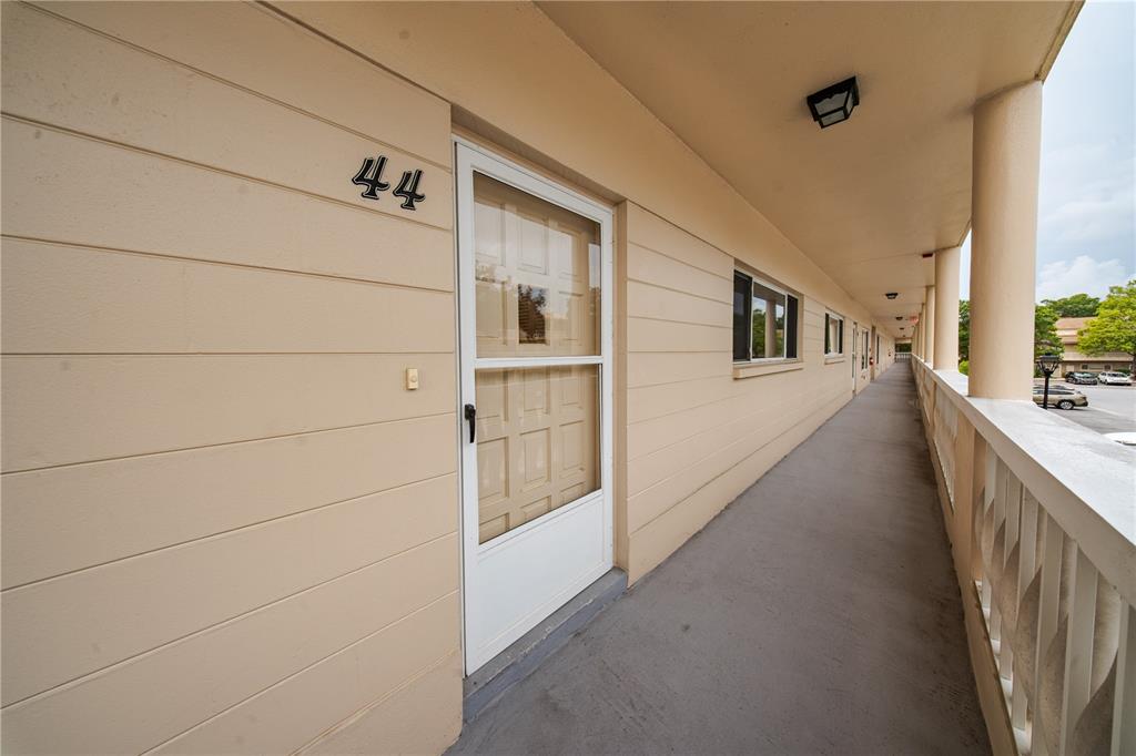An exterior walkway with a white door labeled 44 and a white railing — 2170 AMERICUS BOULEVARD N UNIT 44, CLEARWATER, FL
