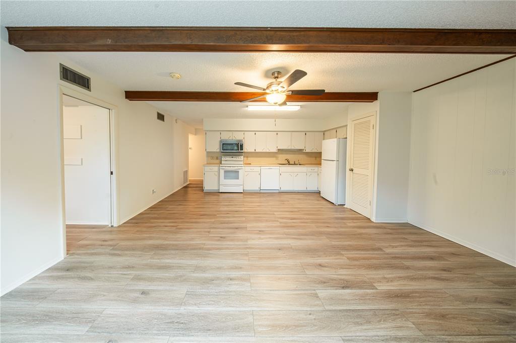 An open-concept kitchen and living area featuring wood-look flooring and exposed ceiling beams — 2170 AMERICUS BOULEVARD N UNIT 44, CLEARWATER, FL
