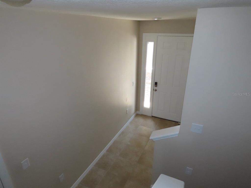 An interior view of an entryway with tile flooring and a white front door — 8725 DAYDREAM STREET, SARASOTA, FL