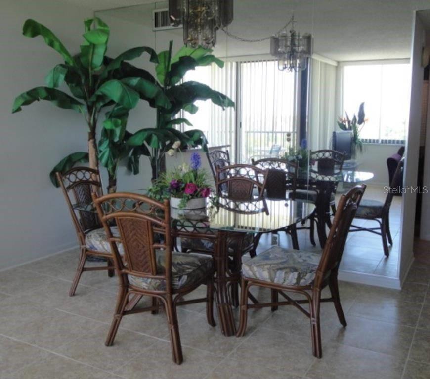 A dining room features a glass-topped rattan table, matching chairs, and a large potted plant — 6104 PALMA DEL MAR BOULEVARD S UNIT 604, ST PETERSBURG, FL