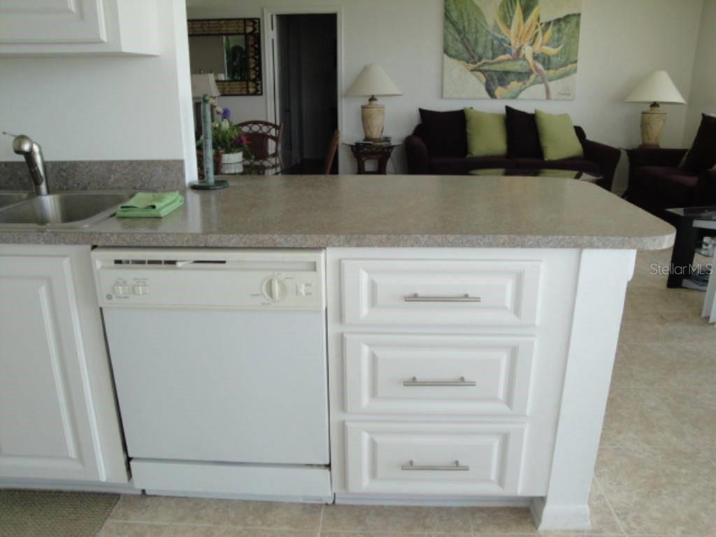 A kitchen island with a dishwasher and drawers sits in front of a living room — 6104 PALMA DEL MAR BOULEVARD S UNIT 604, ST PETERSBURG, FL