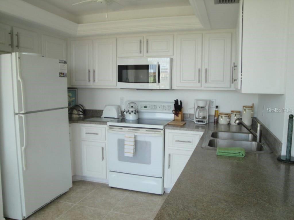 A kitchen features white cabinets, white appliances, and gray countertops — 6104 PALMA DEL MAR BOULEVARD S UNIT 604, ST PETERSBURG, FL