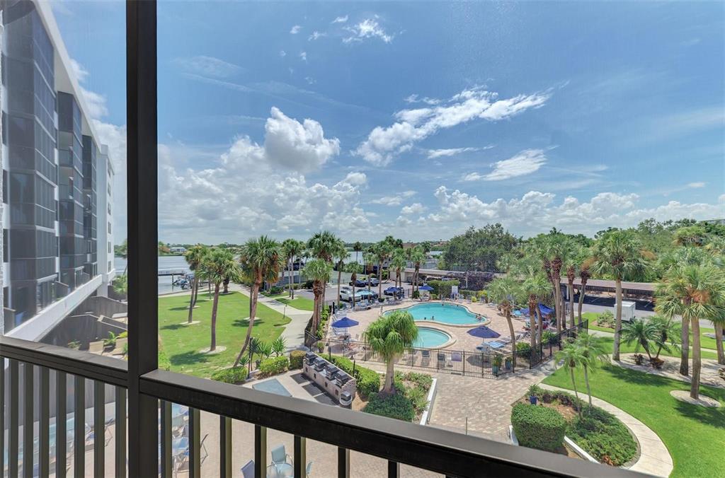 A view from a balcony overlooking a swimming pool, palm trees, and a waterway — 5855 MIDNIGHT PASS ROAD UNIT 333, SARASOTA, FL