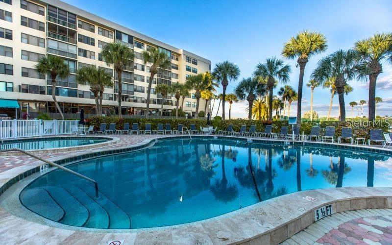 A swimming pool with a stone deck sits in front of a multi-story apartment building — 5855 MIDNIGHT PASS ROAD UNIT 333, SARASOTA, FL