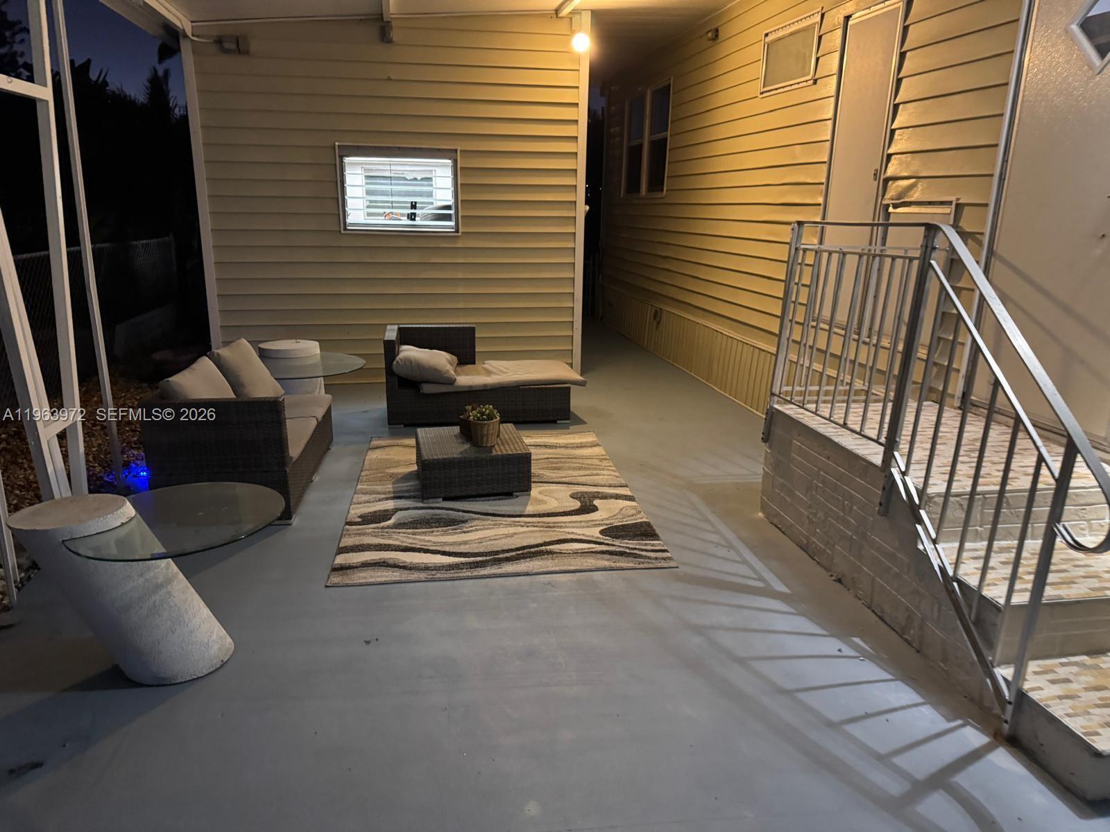 An outdoor patio features wicker furniture, a patterned rug, and stairs leading to a doorway — 1721 SW 84th Ave, Davie FL 33324, DAVIE, FL