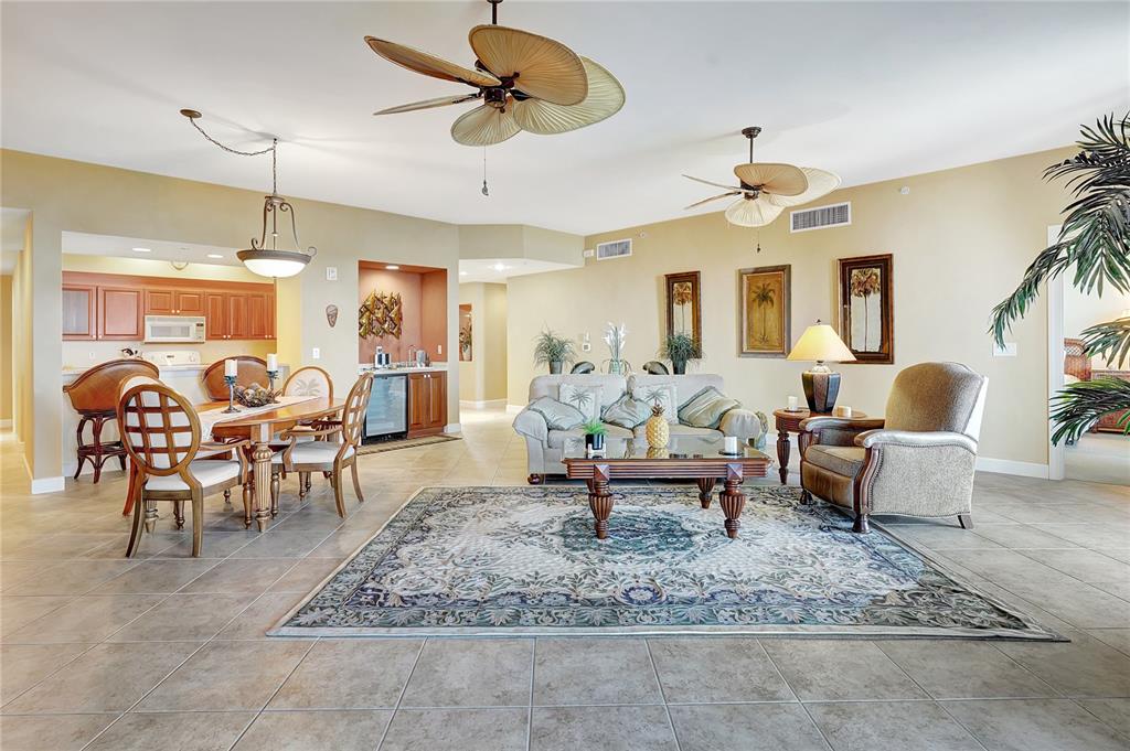 An open-concept living and dining area features tile flooring, two ceiling fans, and neutral walls — 3191 MATECUMBE KEY ROAD UNIT 704, PUNTA GORDA, FL