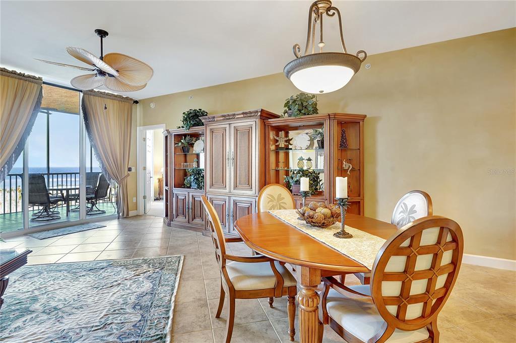 A dining area features a wooden table, chairs, a large hutch, and a balcony view — 3191 MATECUMBE KEY ROAD UNIT 704, PUNTA GORDA, FL