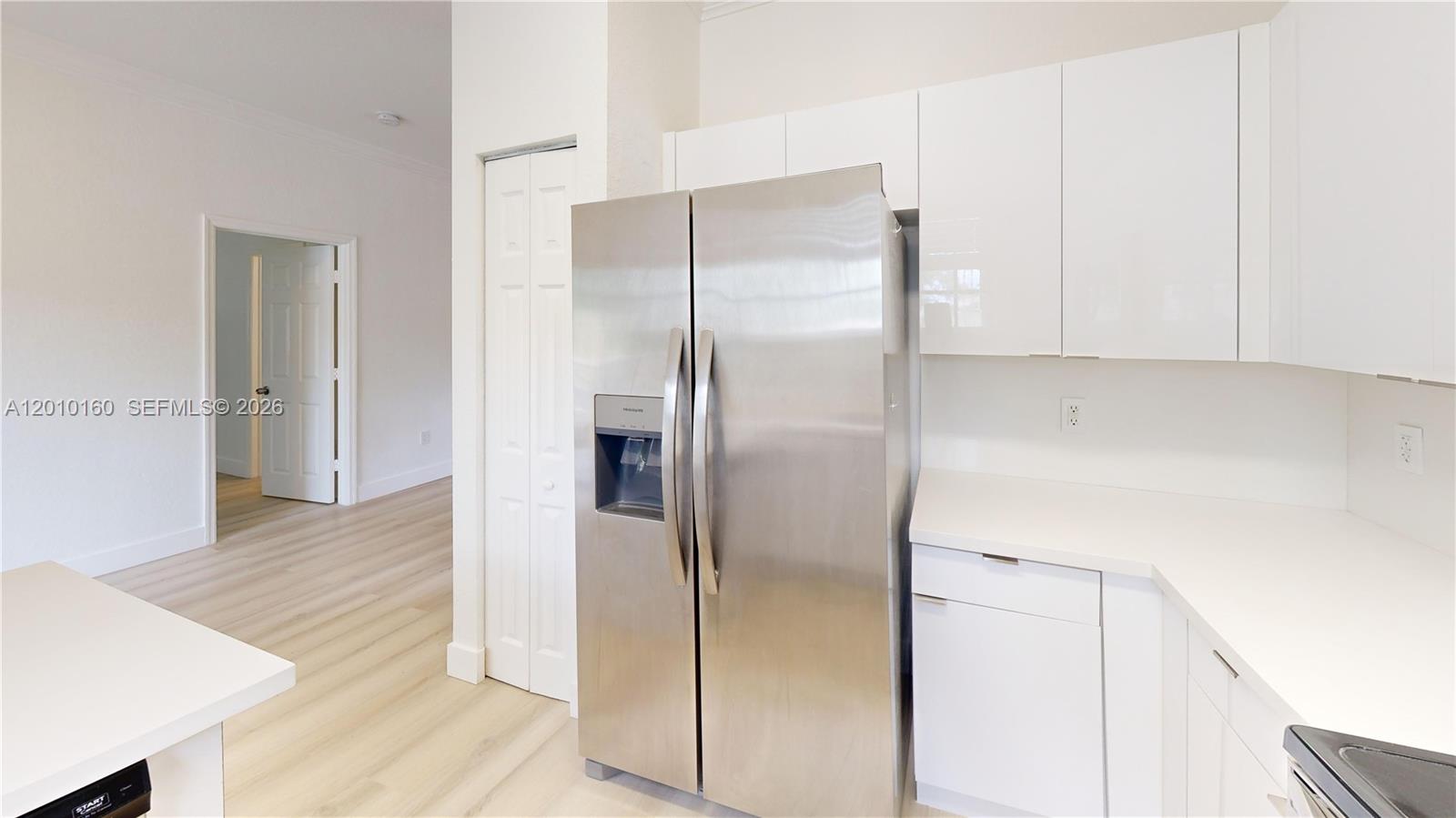 A kitchen features white cabinets, a stainless steel refrigerator, and light wood-look flooring — 372 NE 26th Pl # 201, Homestead FL 33033, HOMESTEAD, FL