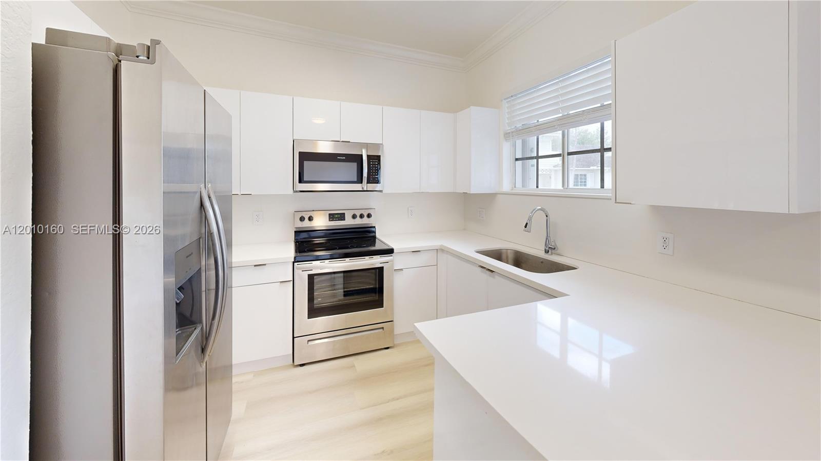 A modern kitchen features white cabinets, stainless steel appliances, and white countertops — 372 NE 26th Pl # 201, Homestead FL 33033, HOMESTEAD, FL
