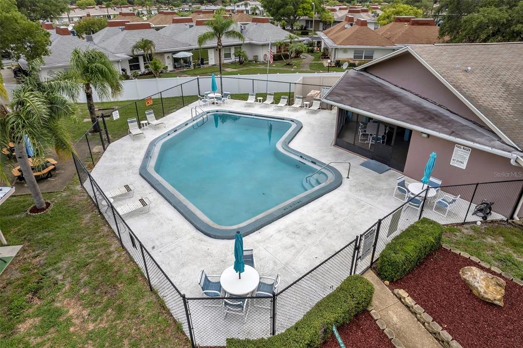 An aerial view of a community swimming pool with lounge chairs and patio tables — 4320 FERN GLEN ST, HOLIDAY, FL