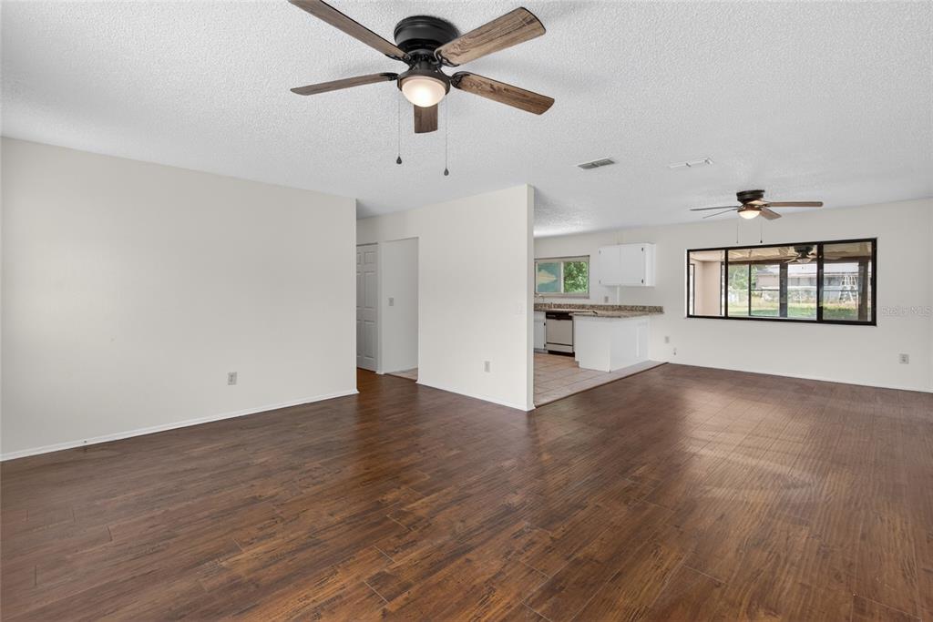 A living room with dark wood-look flooring, white walls, and two ceiling fans — 329 OAK TRACK DRIVE, OCALA, FL