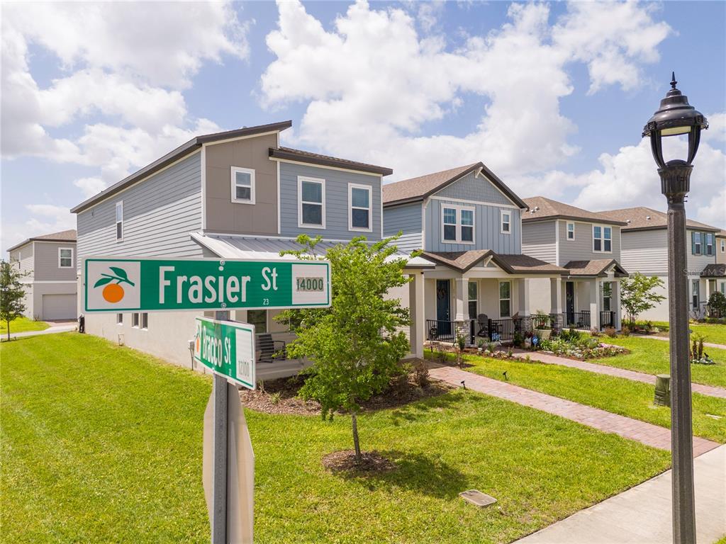 A street sign stands in front of several two-story suburban houses with blue siding — 14006 FRASIER STREET, WINTER GARDEN, FL