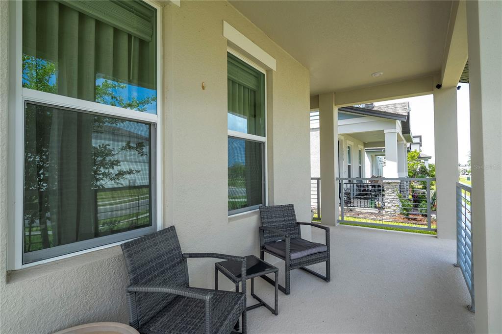 A covered porch features two wicker chairs, a small side table, and metal railings — 14006 FRASIER STREET, WINTER GARDEN, FL