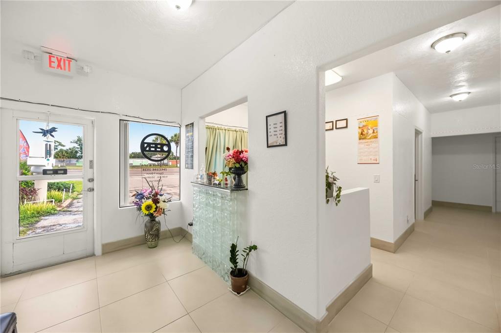 A bright office reception area features a glass block counter, tile flooring, and an exit door — 2081 TAMIAMI TRAIL, PORT CHARLOTTE, FL