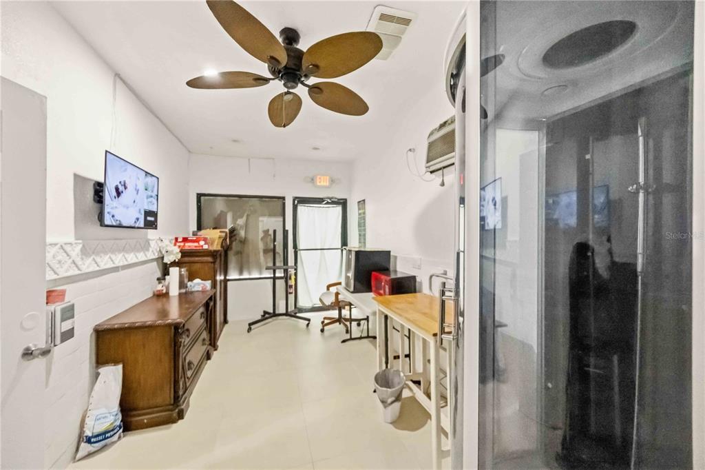 A room with a ceiling fan, a wooden dresser, a table, and a glass shower enclosure — 2081 TAMIAMI TRAIL, PORT CHARLOTTE, FL